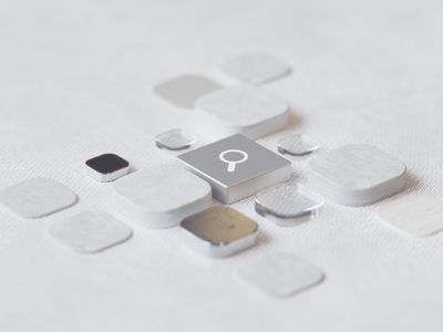 A metallic search-icon key at the center of a grid of blank white and silver app-style tiles on a textured surface